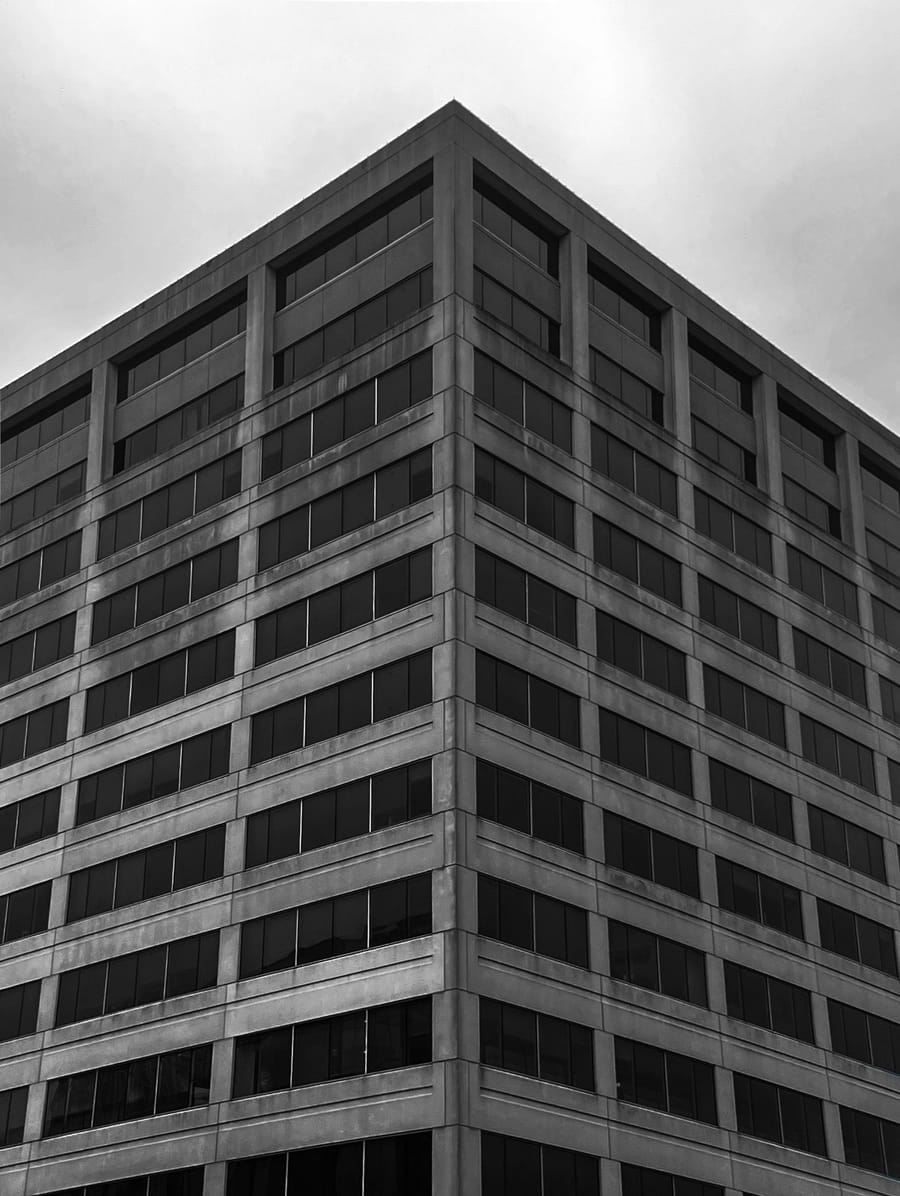 Black and white corner of a concrete office tower against an overcast sky